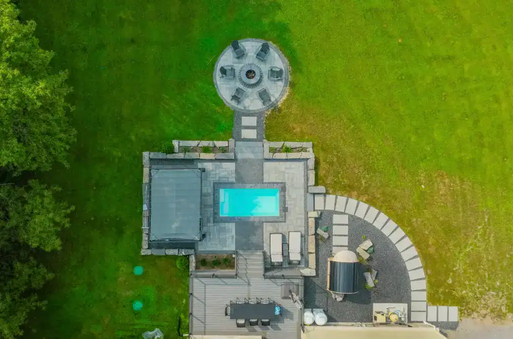 Aerial view of a backyard landscape featuring a pool, patio, hot tub, and outdoor seating area.