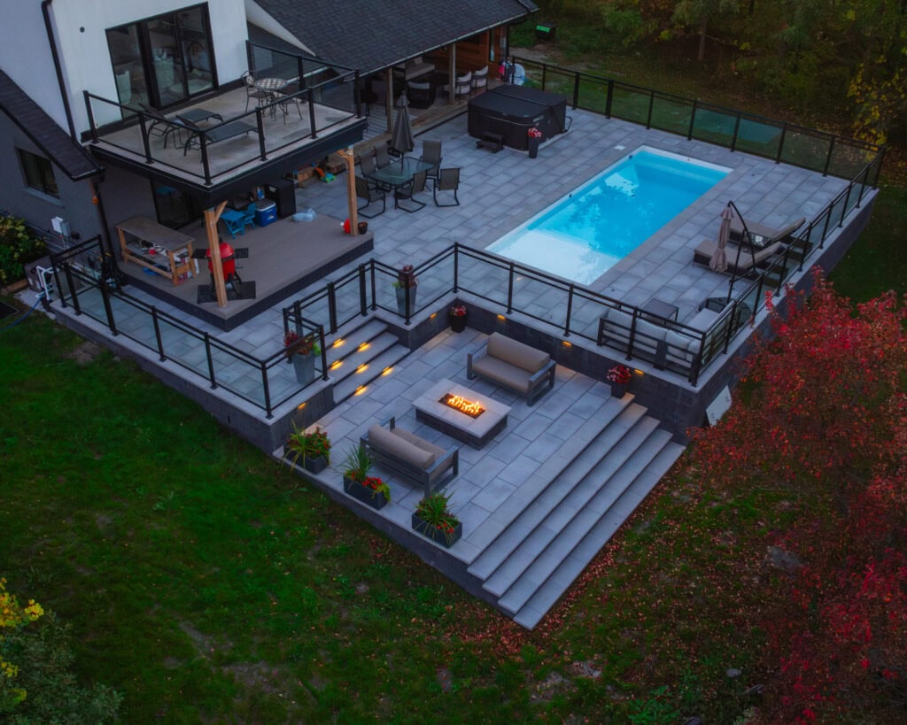 Luxurious outdoor living space featuring a pool, patio, firepit, and landscaped surroundings.