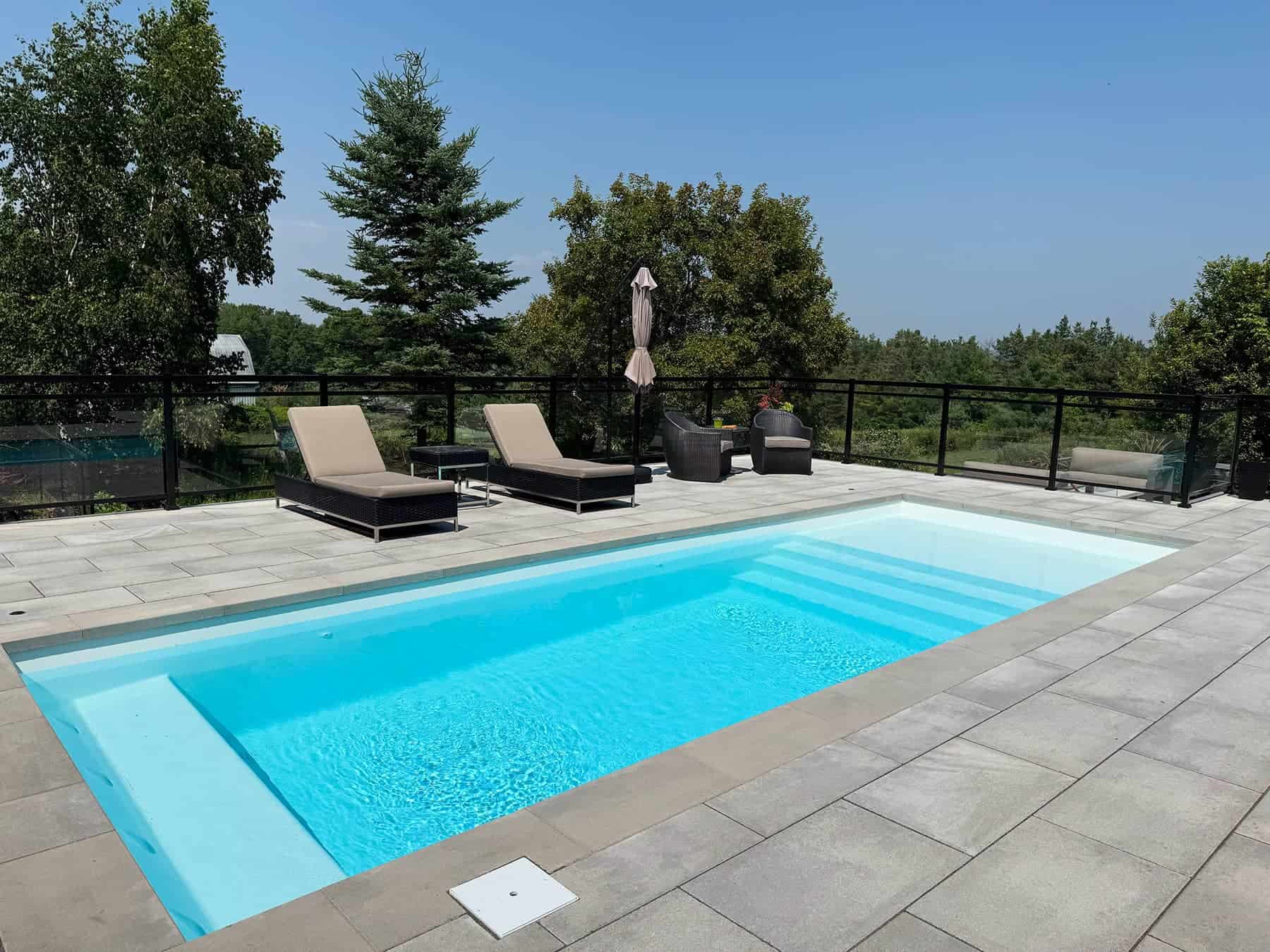 Luxurious backyard pool with loungers, outdoor seating, and scenic landscape view.